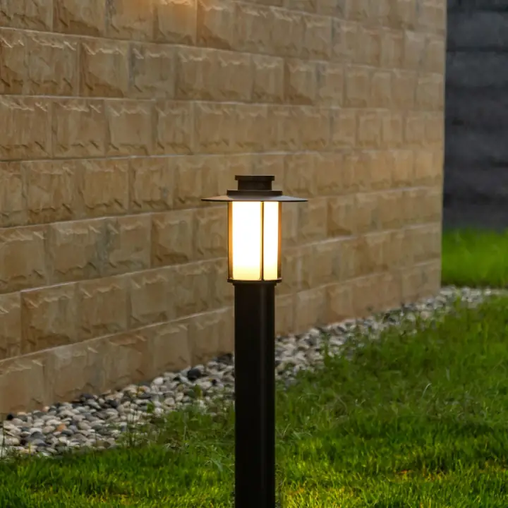 Archaios lantern bollard glowing against a stone wall