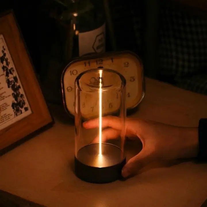 Aura cordless table light glowing beside a vintage clock